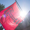 The cherry red Temple T lag waves against a bright sunny and blue sky